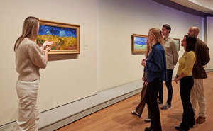 Rondleiding door de tentoonstelling Van Gogh in Auvers. Een groepje bezoekers luistert naar de gids bij het schilderij Korenveld met kraaien. Foto: Michael Floor