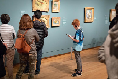 Een roodharige  jongen met audiotour tussen andere bezoekers in het Van Gogh Museum. Foto Brenda Roos